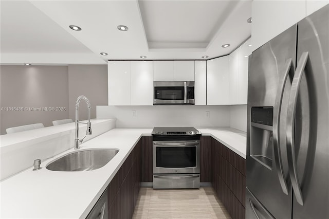 401 Ocean Dr Unit 221, Miami Beach, FL 33139 - kitchen featuring stainless steel appliances, modern cabinets, a sink, white cabinetry, and light countertops