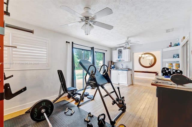 717 SW Aster Rd, Port St Lucie, FL 34953 - exercise room with light wood-style flooring, ceiling fan, a textured ceiling, and baseboards