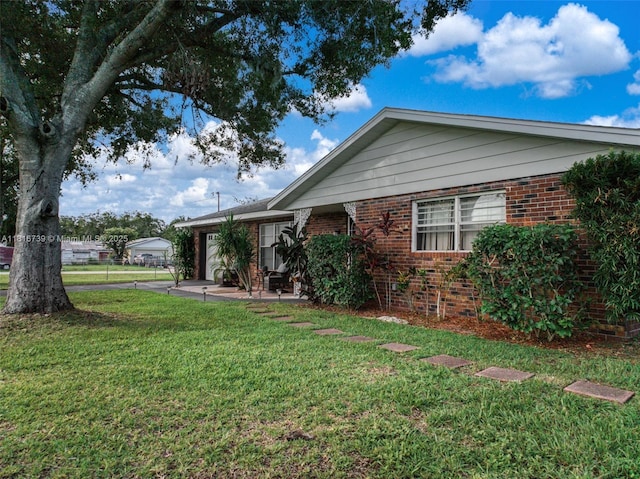 2430 N Dunwoodie Rd, Avon Park, FL 33825 - view of home's exterior with brick siding, an attached garage, a yard, driveway, and a patio area