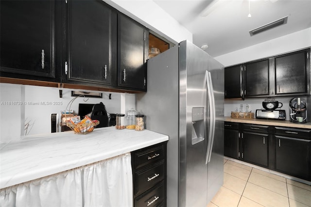 2430 N Dunwoodie Rd, Avon Park, FL 33825 - kitchen with dark cabinetry, light countertops, light tile patterned floors, and stainless steel refrigerator with ice dispenser