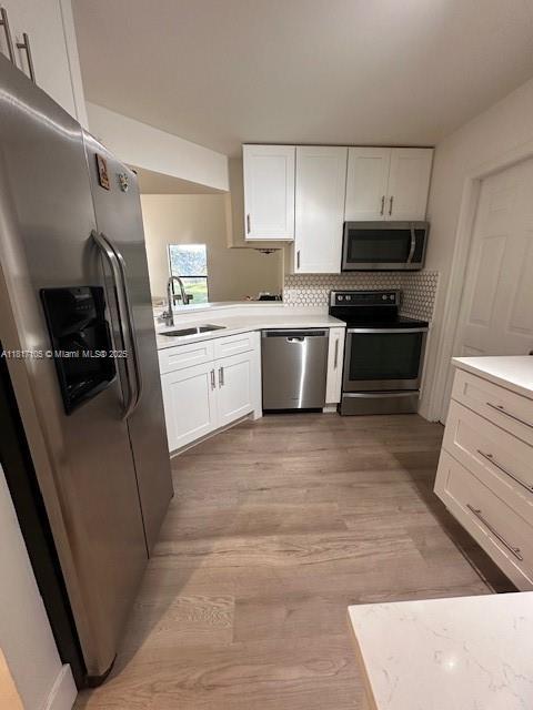 12 Via De Casas Sur Unit 104, Boynton Beach, FL 33426 - kitchen with stainless steel appliances, a sink, white cabinets, and light countertops