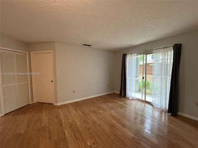3705SW 27 Th St Unit 416, Gainesville, FL 32608 - unfurnished bedroom featuring access to exterior, a textured ceiling, baseboards, and wood finished floors
