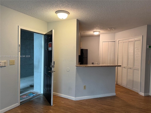 3705SW 27 Th St Unit 416, Gainesville, FL 32608 - kitchen with wood finished floors, freestanding refrigerator, a textured ceiling, and baseboards