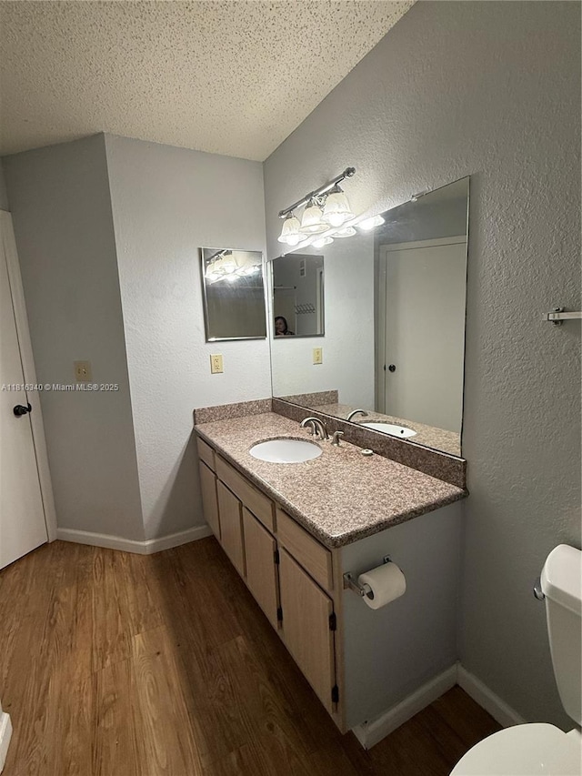 3705SW 27 Th St Unit 416, Gainesville, FL 32608 - half bathroom featuring wood finished floors, vanity, toilet, a textured wall, and a textured ceiling