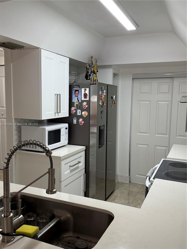 6560 SW 138th Ct Unit 804, Miami, FL 33183 - kitchen featuring lofted ceiling, white cabinetry, white microwave, light countertops, and electric range