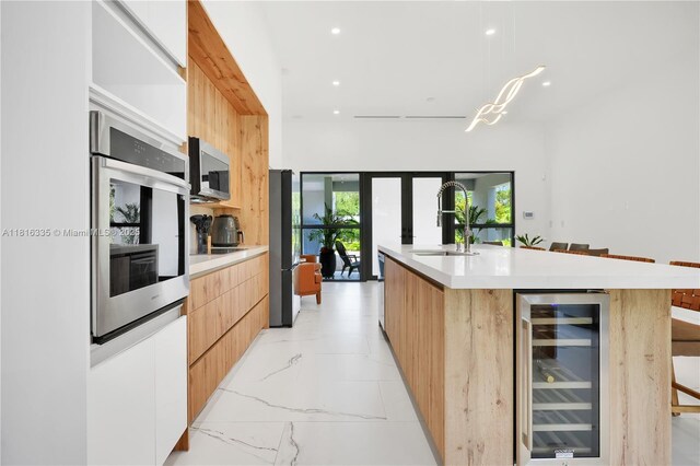 1902 Della Dr, Naples, FL 34117 - kitchen featuring modern cabinets, beverage cooler, appliances with stainless steel finishes, a sink, and light countertops