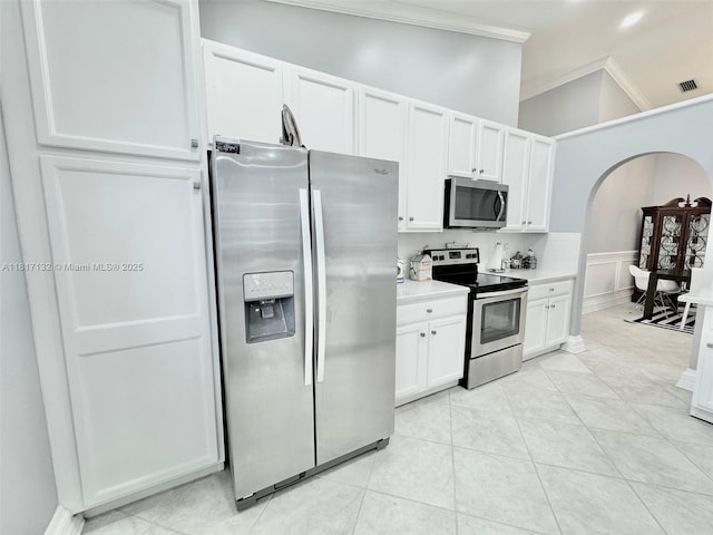 1136 SE Westminster Pl, Stuart, FL 34997 - kitchen with stainless steel appliances, crown molding, light countertops, white cabinets, and arched walkways