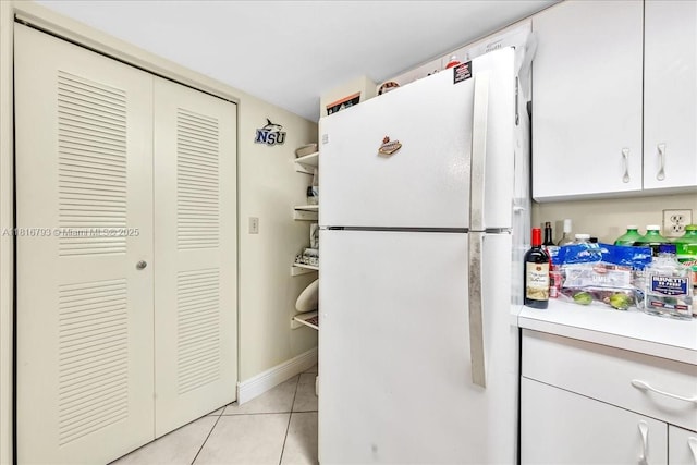 2351 Douglas Rd Unit 1204, Miami, FL 33145 - kitchen featuring freestanding refrigerator, light tile patterned flooring, light countertops, white cabinets, and baseboards