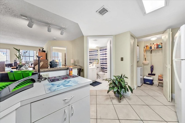 2351 Douglas Rd Unit 1204, Miami, FL 33145 - kitchen featuring separate washer and dryer, rail lighting, light tile patterned floors, white cabinetry, and light countertops