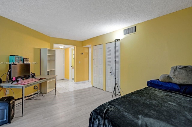 6555 W Broward Blvd Unit 412, Plantation, FL 33317 - bedroom featuring light wood-style flooring, a textured ceiling, and multiple closets
