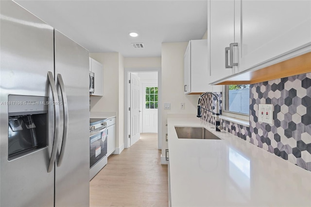 8510 SE Citrus Way, Hobe Sound, FL 33455 - kitchen with stainless steel appliances, a sink, light countertops, white cabinetry, and recessed lighting