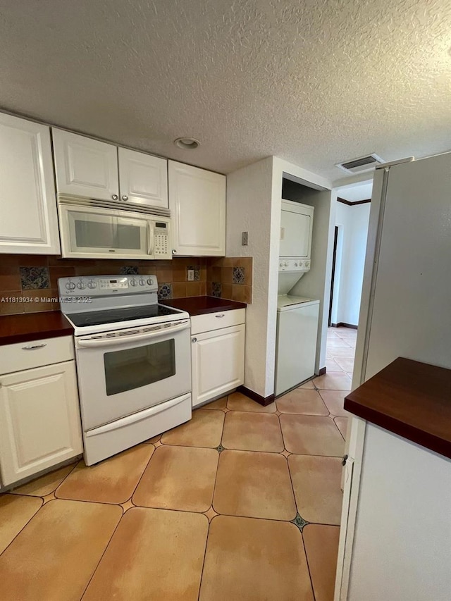 6575 W Oakland Park Blvd Unit 511, Lauderhill, FL 33313 - kitchen featuring white appliances, stacked washer and clothes dryer, dark countertops, white cabinets, and a textured ceiling