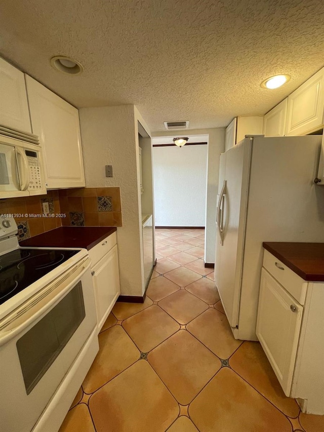 6575 W Oakland Park Blvd Unit 511, Lauderhill, FL 33313 - kitchen featuring white appliances, dark countertops, white cabinetry, a textured ceiling, and decorative backsplash