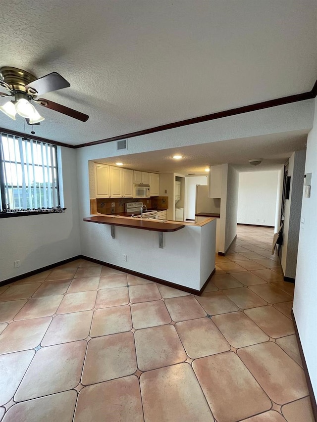 6575 W Oakland Park Blvd Unit 511, Lauderhill, FL 33313 - kitchen with a peninsula, white microwave, ceiling fan, refrigerator, and a breakfast bar area
