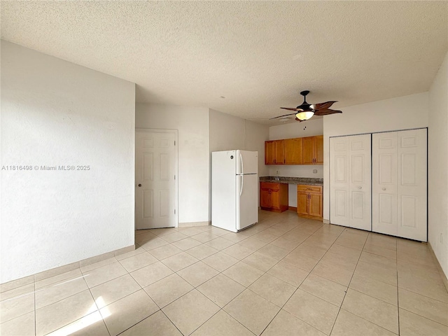 14945 SW 38th St, Miami, FL 33185 - kitchen with freestanding refrigerator, ceiling fan, light tile patterned floors, brown cabinets, and a textured ceiling