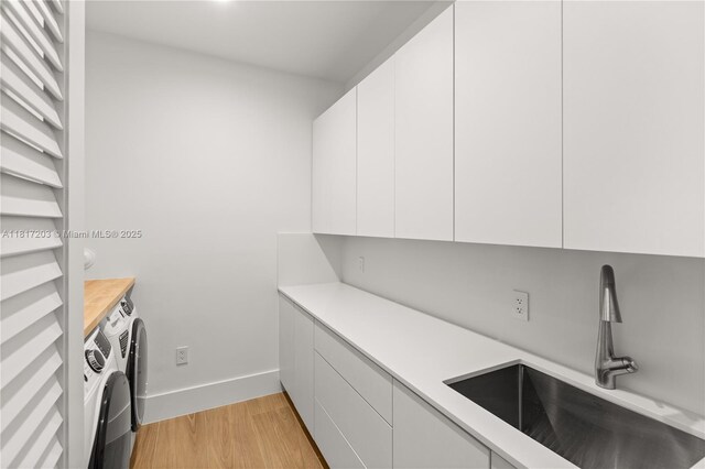 8811 SW 56th St, Miami, FL 33165 - laundry area featuring separate washer and dryer, cabinet space, light wood-type flooring, and baseboards