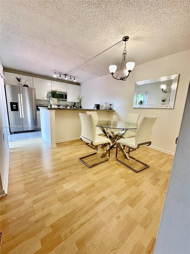 4306 43rd Way, West Palm Beach, FL 33407 - dining space with light wood finished floors, track lighting, a textured ceiling, baseboards, and a chandelier