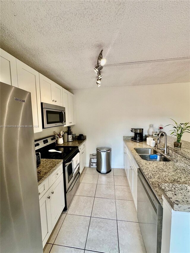4306 43rd Way, West Palm Beach, FL 33407 - kitchen featuring appliances with stainless steel finishes, a sink, white cabinets, light tile patterned floors, and light stone counters