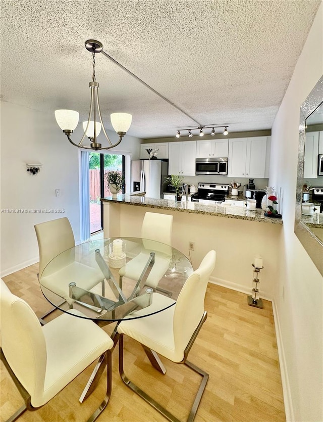 4306 43rd Way, West Palm Beach, FL 33407 - dining area with rail lighting, a textured ceiling, a chandelier, and light wood-type flooring