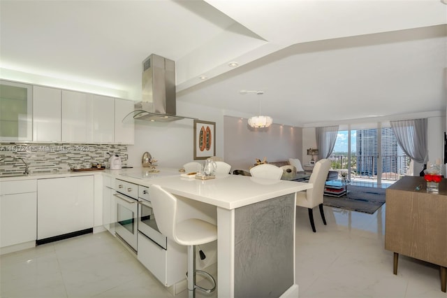 18151 NE 31st Ct Unit 1905, Aventura, FL 33160 - kitchen featuring island exhaust hood, modern cabinets, tasteful backsplash, a peninsula, and white cabinets