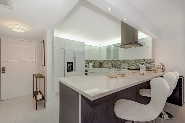18151 NE 31st Ct Unit 1905, Aventura, FL 33160 - kitchen with island range hood, a breakfast bar area, a peninsula, decorative backsplash, and recessed lighting