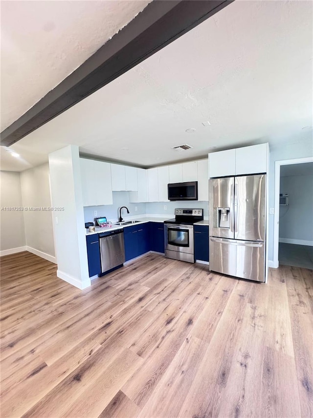 3731 SW 58th Ter, Davie, FL 33314 - kitchen with stainless steel appliances, light countertops, light wood finished floors, white cabinets, and blue cabinetry