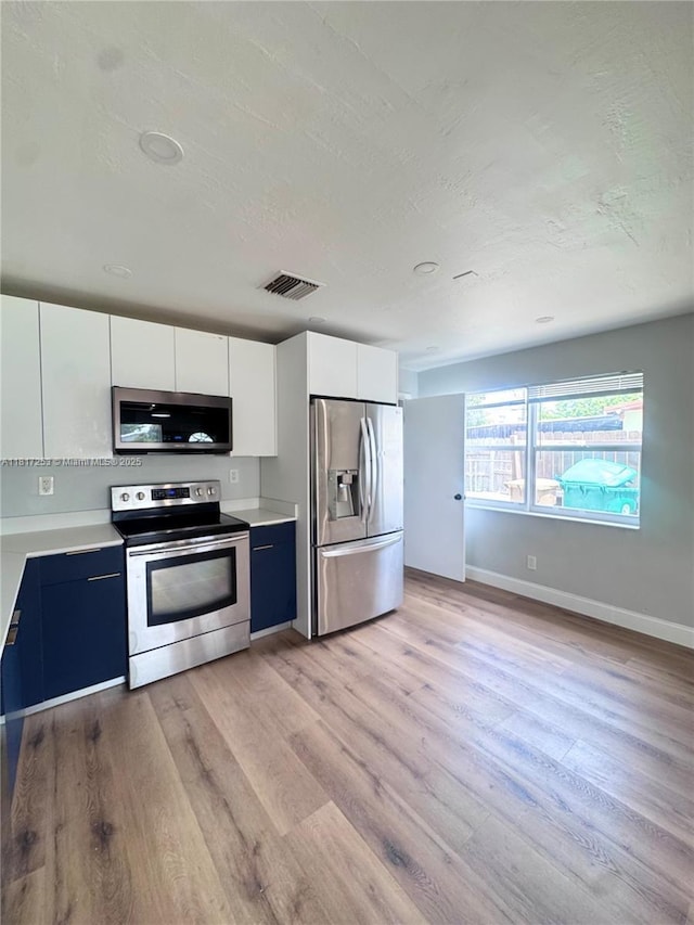 3731 SW 58th Ter, Davie, FL 33314 - kitchen featuring appliances with stainless steel finishes, light wood finished floors, light countertops, white cabinets, and a textured ceiling