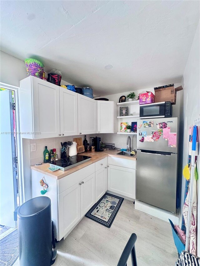 3731 SW 58th Ter, Davie, FL 33314 - kitchen with freestanding refrigerator, black electric cooktop, white cabinetry, and light countertops