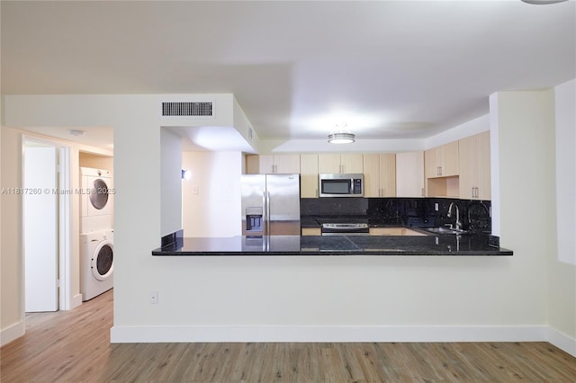 5845 Collins Ave Unit 304, Miami Beach, FL 33140 - kitchen with stainless steel appliances, a sink, stacked washing machine and dryer, and baseboards