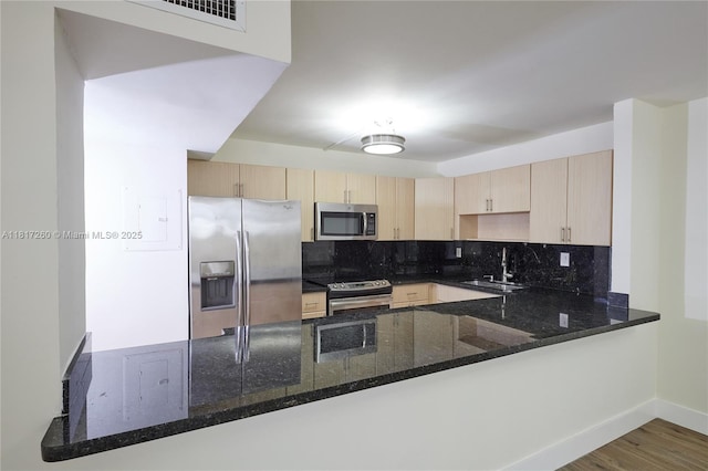 5845 Collins Ave Unit 304, Miami Beach, FL 33140 - kitchen featuring stainless steel appliances, light brown cabinetry, a sink, a peninsula, and dark stone counters