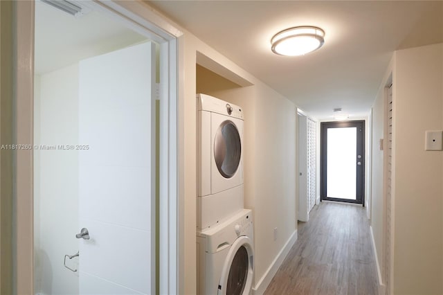 5845 Collins Ave Unit 304, Miami Beach, FL 33140 - laundry room featuring stacked washing machine and dryer, baseboards, and light wood finished floors