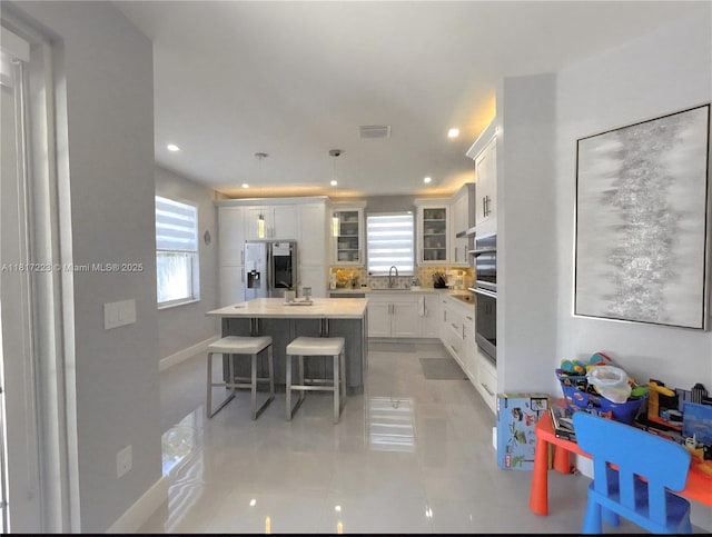 14121 SW 152nd Ter, Miami, FL 33177 - kitchen featuring stainless steel appliances, light tile patterned floors, a breakfast bar area, a center island, and white cabinetry