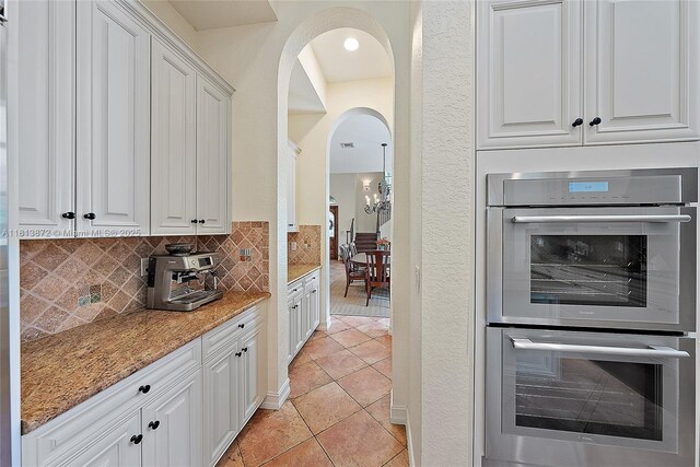 112 Segovia Way, Jupiter, FL 33458 - kitchen with stainless steel double oven, white cabinets, tasteful backsplash, and light tile patterned flooring
