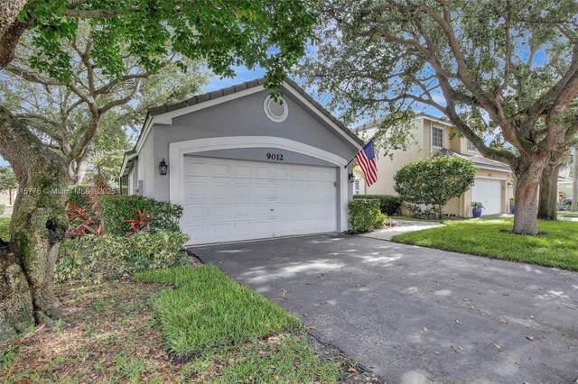 9012 Lake Park Cir S, Davie, FL 33328 - view of front facade featuring stucco siding, driveway, and a garage