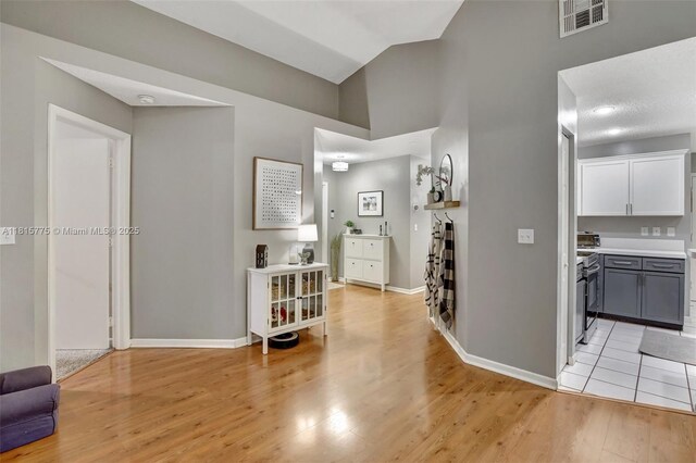 9012 Lake Park Cir S, Davie, FL 33328 - hall with light wood finished floors, baseboards, and high vaulted ceiling