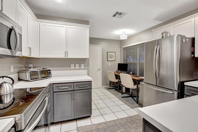 9012 Lake Park Cir S, Davie, FL 33328 - kitchen featuring appliances with stainless steel finishes, white cabinets, light countertops, a textured ceiling, and an office area
