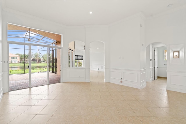 7215 Great Falls Cir, Boynton Beach, FL 33437 - spare room featuring arched walkways, crown molding, light tile patterned floors, a decorative wall, and wainscoting