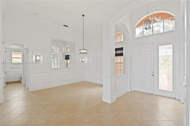 7215 Great Falls Cir, Boynton Beach, FL 33437 - foyer entrance featuring arched walkways, a decorative wall, light tile patterned floors, a towering ceiling, and crown molding