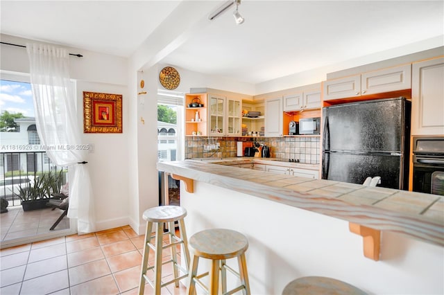 1455 W Ave Unit 202, Miami Beach, FL 33139 - kitchen featuring black appliances, open shelves, a breakfast bar, light tile patterned floors, and backsplash