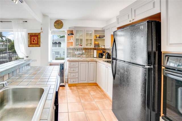 1455 W Ave Unit 202, Miami Beach, FL 33139 - kitchen with black appliances, tile countertops, open shelves, a sink, and backsplash