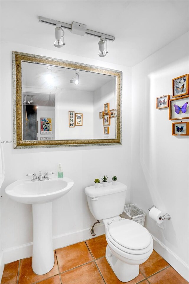 1455 W Ave Unit 202, Miami Beach, FL 33139 - half bath featuring tile patterned floors, toilet, baseboards, and rail lighting