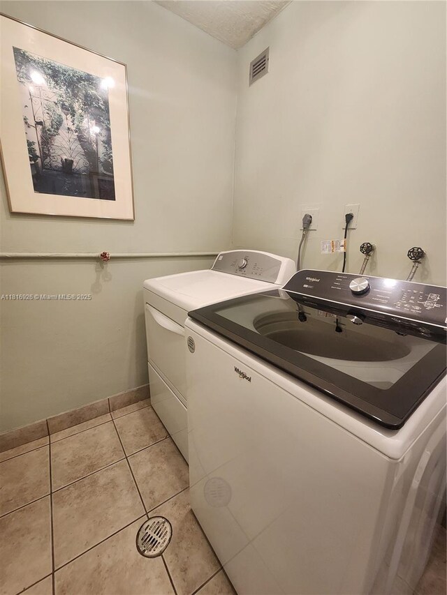1455 W Ave Unit 202, Miami Beach, FL 33139 - laundry room featuring washer and clothes dryer, light tile patterned flooring, and baseboards
