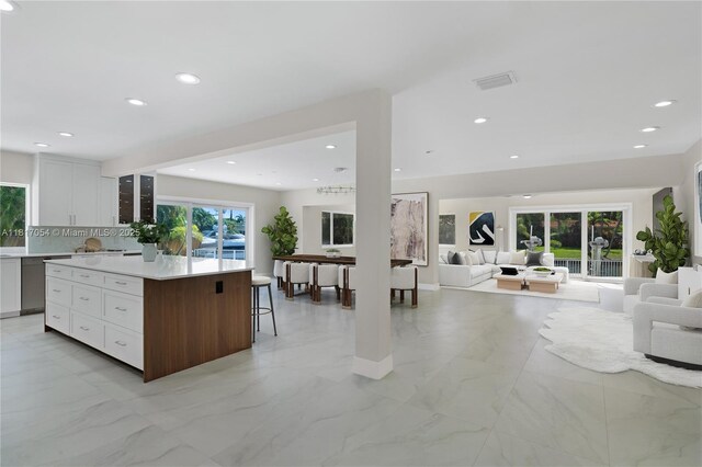 12985 Ortega Ln, North Miami, FL 33181 - kitchen with open floor plan, light marble finish floors, a center island, white cabinets, and light countertops