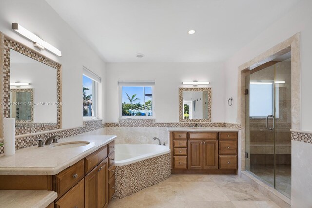 12985 Ortega Ln, North Miami, FL 33181 - full bathroom featuring two vanities, a bath, a shower stall, tile patterned flooring, and recessed lighting
