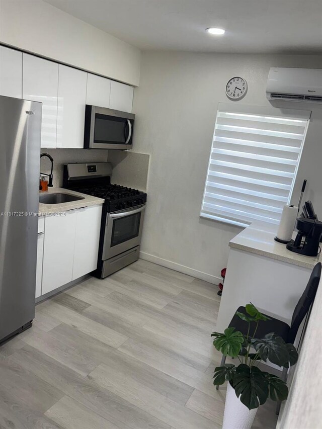 251 NW 57th Ave, Miami, FL 33126 - kitchen with stainless steel appliances, an AC wall unit, a sink, white cabinetry, and recessed lighting