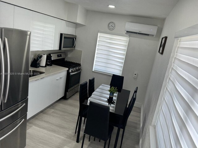 251 NW 57th Ave, Miami, FL 33126 - kitchen featuring appliances with stainless steel finishes, a wall unit AC, white cabinets, light countertops, and light wood-style floors