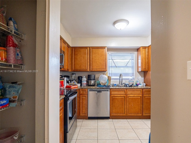 4915 Pine Needle Dr, Orlando, FL 32808 - kitchen with appliances with stainless steel finishes, brown cabinetry, light tile patterned floors, a sink, and light stone counters