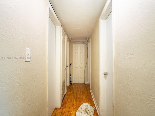 4915 Pine Needle Dr, Orlando, FL 32808 - hall with light wood-type flooring, a textured wall, and baseboards