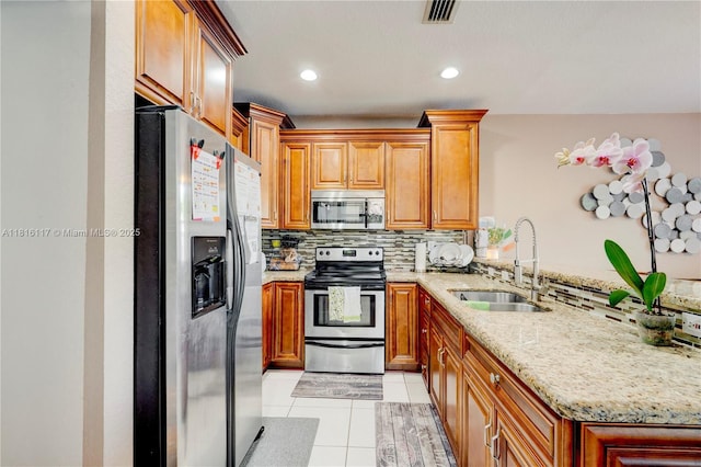 1100 SE 19th Ave, Homestead, FL 33035 - kitchen featuring appliances with stainless steel finishes, decorative backsplash, light stone counters, light tile patterned floors, and a peninsula