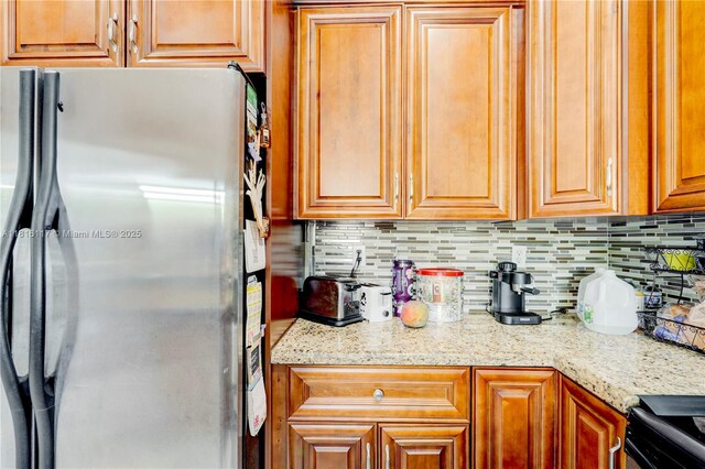 1100 SE 19th Ave, Homestead, FL 33035 - kitchen with freestanding refrigerator, backsplash, range with electric stovetop, and light stone countertops